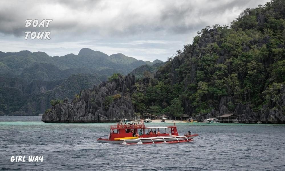 A red outrigger boat navigates open water near dramatic limestone cliffs, illustrating How to Get to Balabac, Palawan safely.